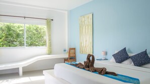 A bedroom with a large window, a bed with a blue towel, a chair, a nightstand, and a wall with a large painting. - KeereeLay (Ko Lanta)