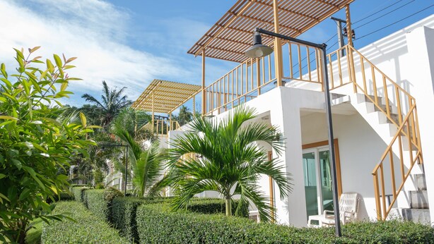 A modern building with a white exterior, a wooden staircase, and a covered outdoor area. - KeereeLay (Ko Lanta)
