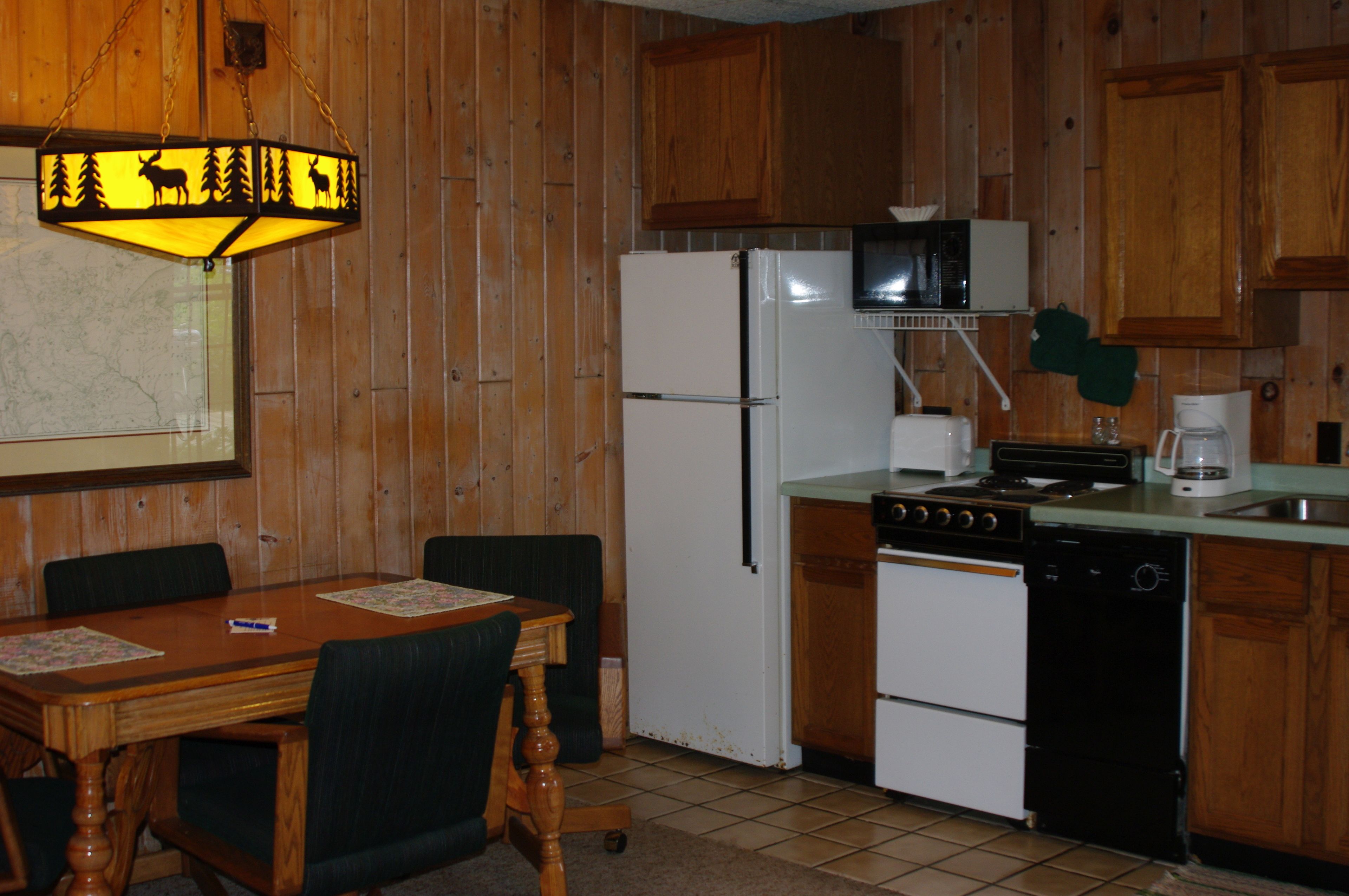 A kitchen with wooden cabinets, a refrigerator, a stove, a dishwasher, and a microwave.