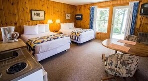 A cozy cabin-style room with two beds, a dining table, and a kitchenette.