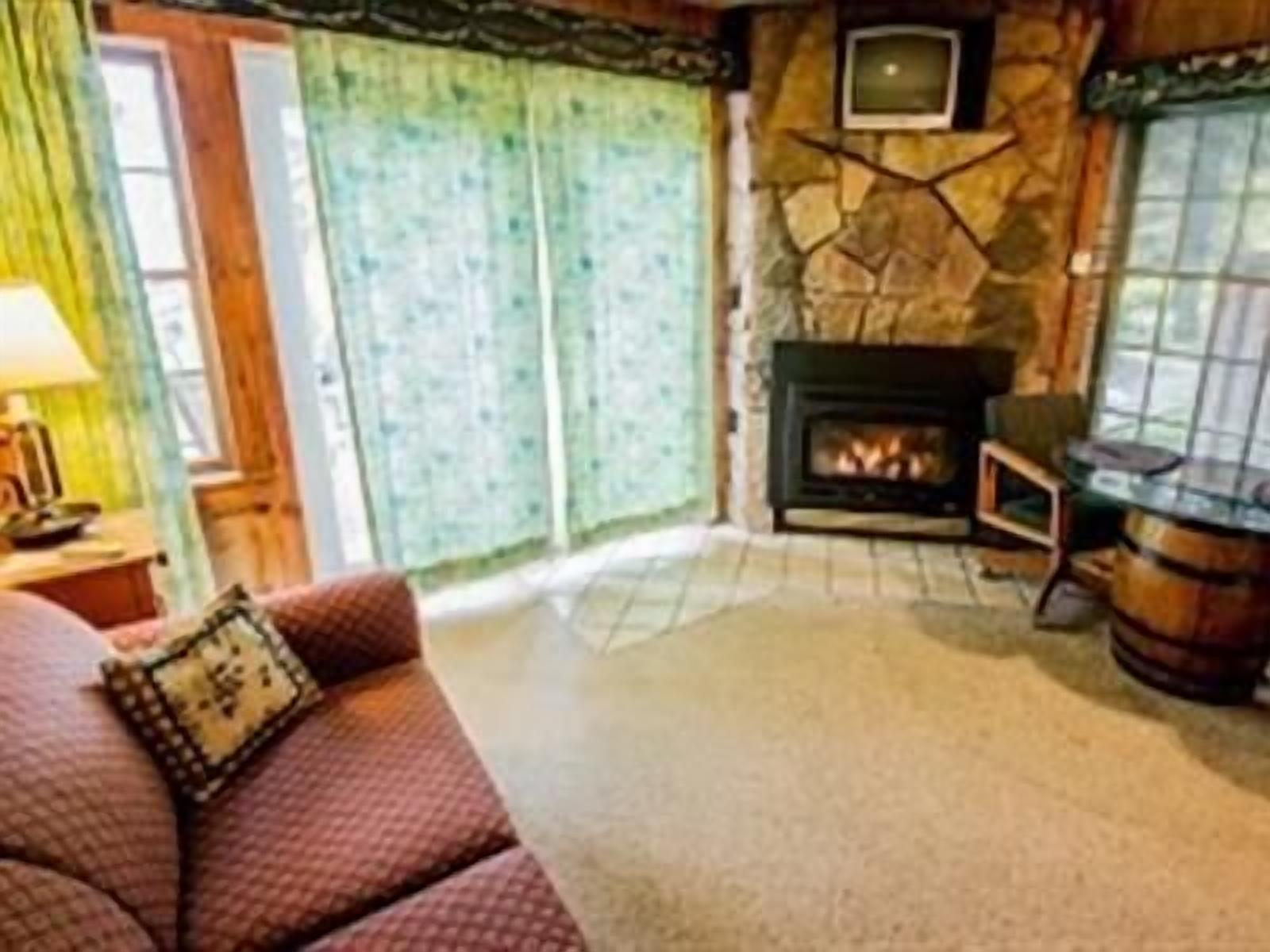 A cozy living room with a fireplace, a sofa, and a television mounted on the wall.