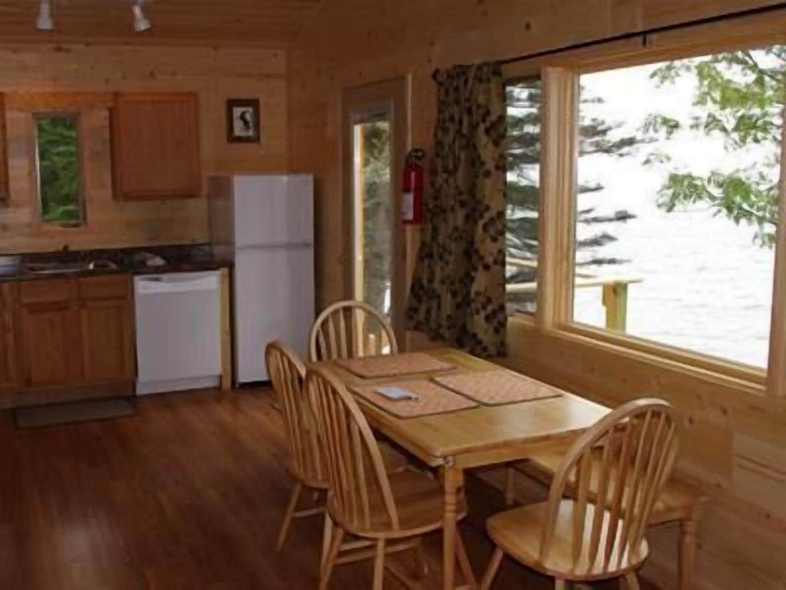Una cocina estilo cabaña con armarios de madera, un refrigerador y una mesa de comedor con sillas.