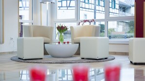 Ein modernes Wohnzimmer mit einem weißen Sofasatz, einem Couchtisch in der Mitte und einer Vase mit Blumen.