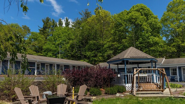 A hotel with a covered patio area, outdoor seating, and a swing set. - Blowing Rock Inn (Blowing Rock)
