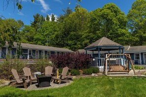 A hotel with a covered patio area, outdoor seating, and a swing set.