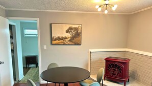 A dining area with a round table and four chairs, a fireplace with a red stove, and a painting on the wall. - Blowing Rock Inn (Blowing Rock)