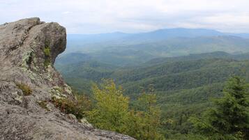 A mountainous landscape with a rocky outcrop and dense forest.