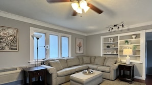 A living room with a sectional sofa, a ceiling fan, a patterned rug, and a built-in shelving unit. - Blowing Rock Inn (Blowing Rock)