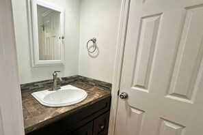 A bathroom with a white sink, a mirror, and a door.