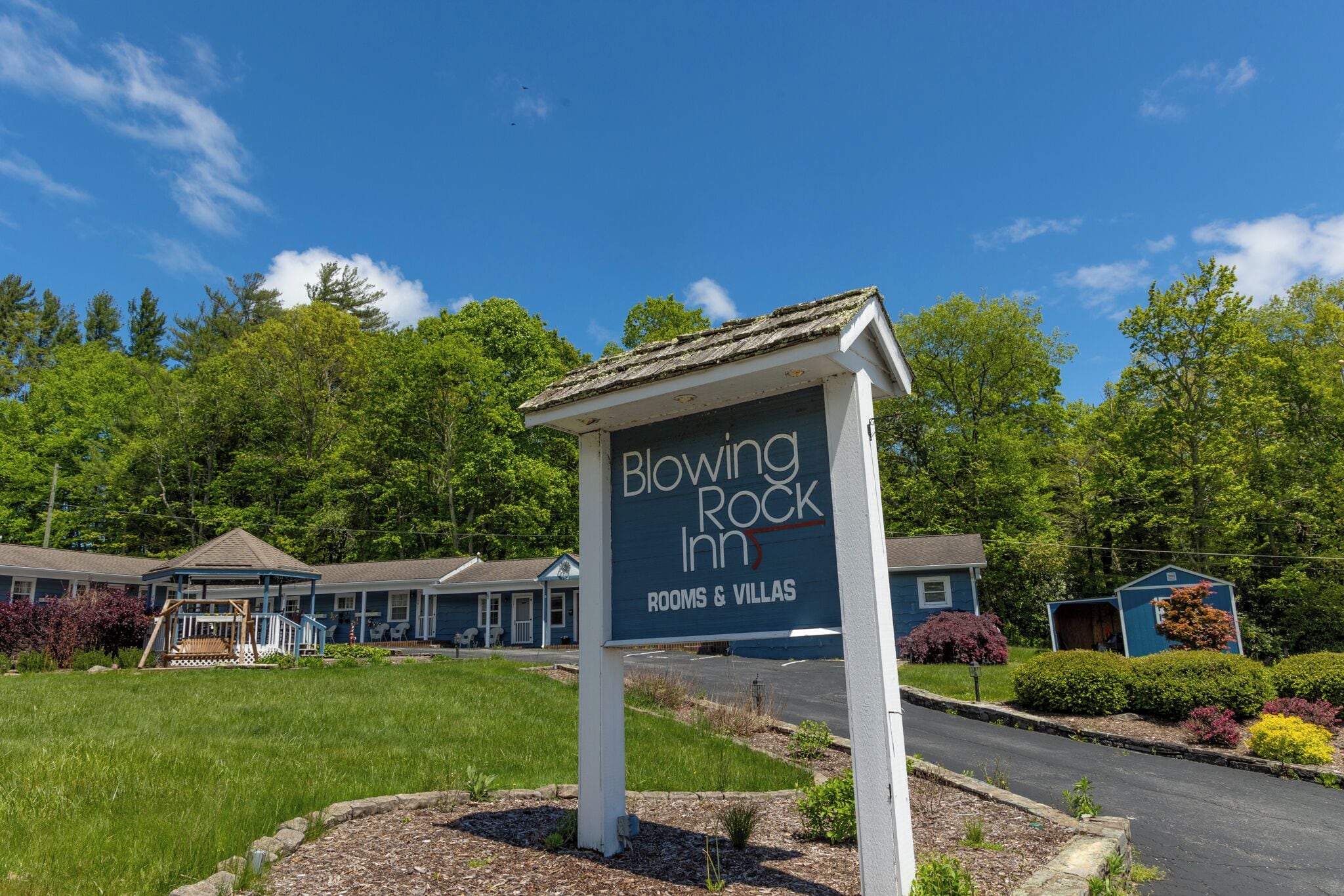 A sign for Blowing Rock Inn with a view of the property, including a building and a parking area.