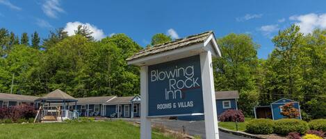 A sign for Blowing Rock Inn with a view of the property, including a building and a parking area.