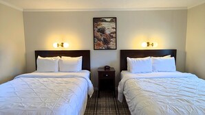 A hotel room with two beds, a nightstand, a painting on the wall, and a patterned carpet. - Blowing Rock Inn (Blowing Rock)