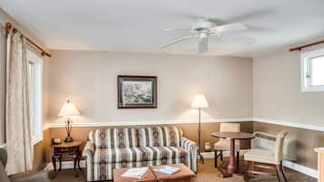 A living room with a sofa, two armchairs, a coffee table, a ceiling fan, and two lamps.
