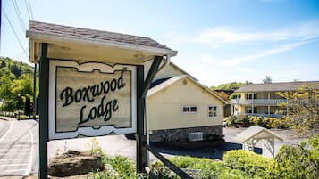 Une enseigne en bois indiquant l’emplacement de Boxwood Lodge, avec une base en pierre et un petit porche.