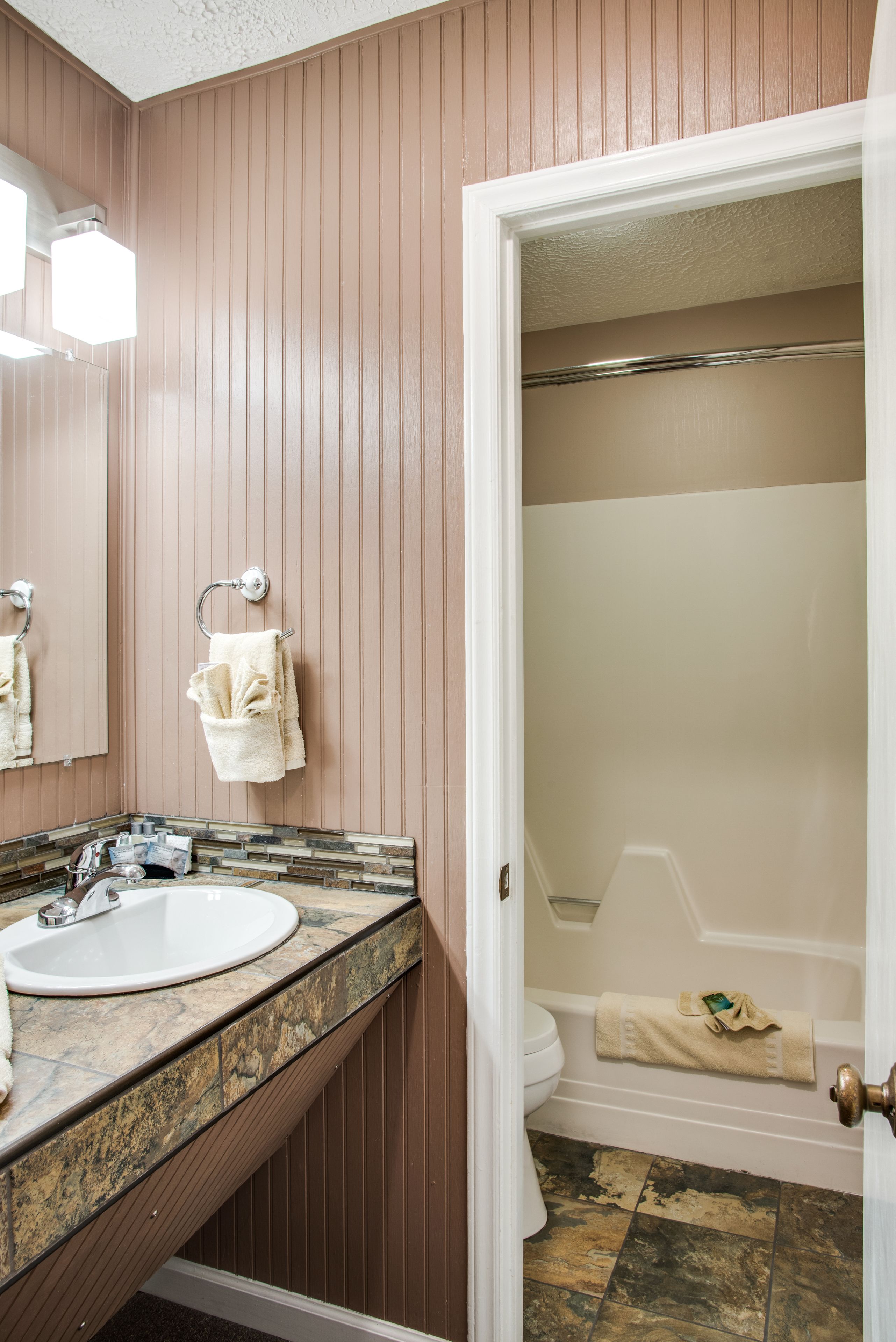 A bathroom with a sink, mirror, towel rack, and a bathtub.