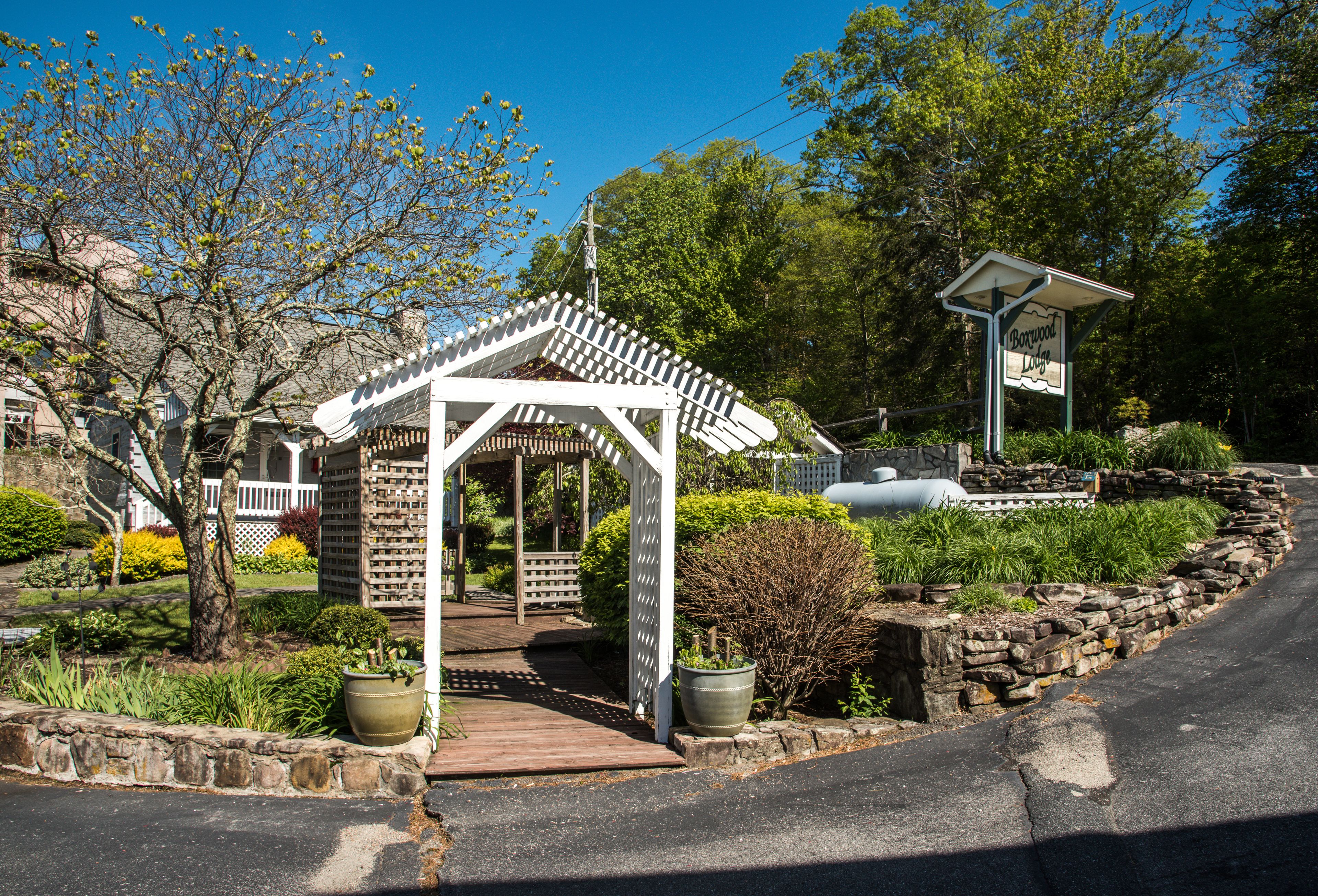 A gazebo with a wooden deck, surrounded by stone walls and potted plants.