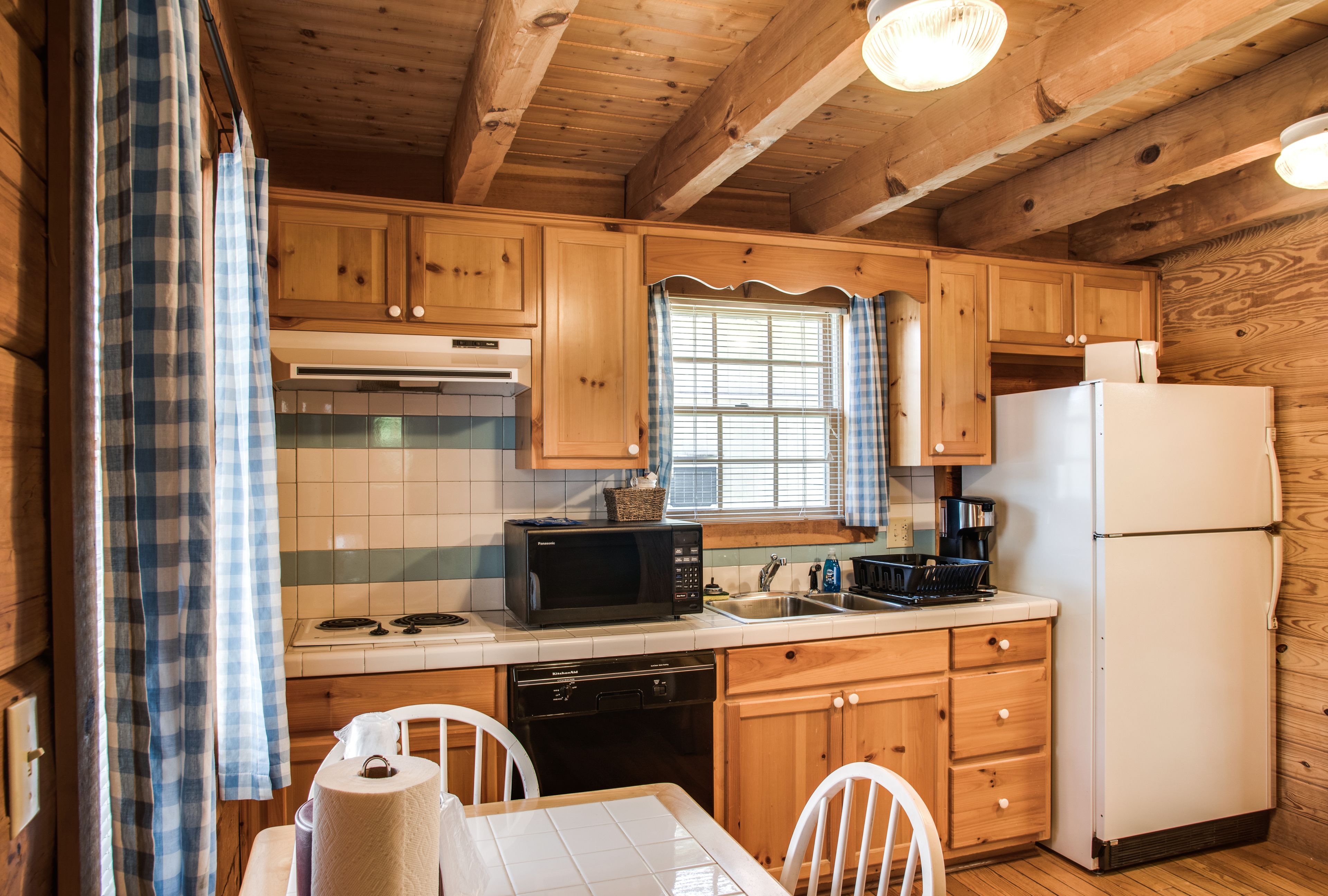 Cocina de cabaña de madera con microondas, estufa, lavabo y refrigerador.