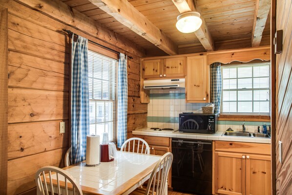 A wooden cabin kitchen with a dining table, chairs, a microwave, and a dishwasher.