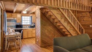 Un intérieur de chalet chaleureux comprenant une cuisine, un coin repas et un escalier menant à un niveau supérieur.