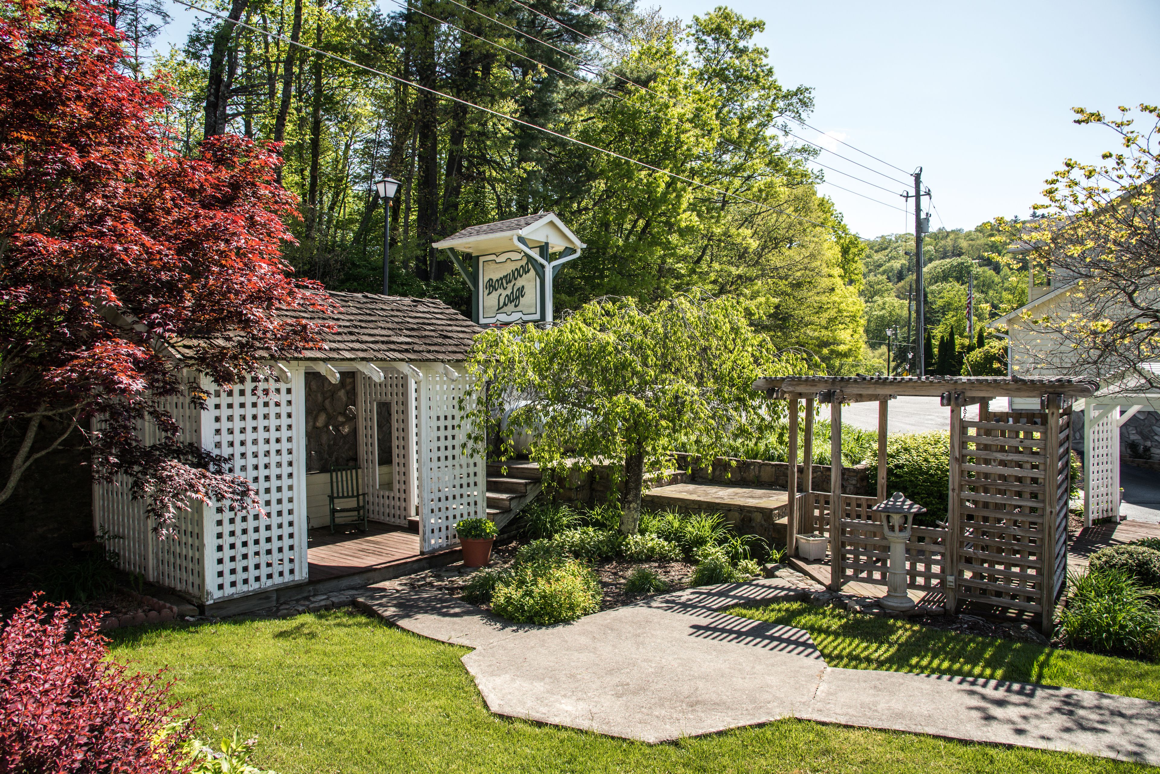 A small lodge with a wooden deck, a gazebo, and a sign that reads "Borewood Lodge."