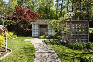 Un jardín con un pabellón, un sendero y una pérgola.