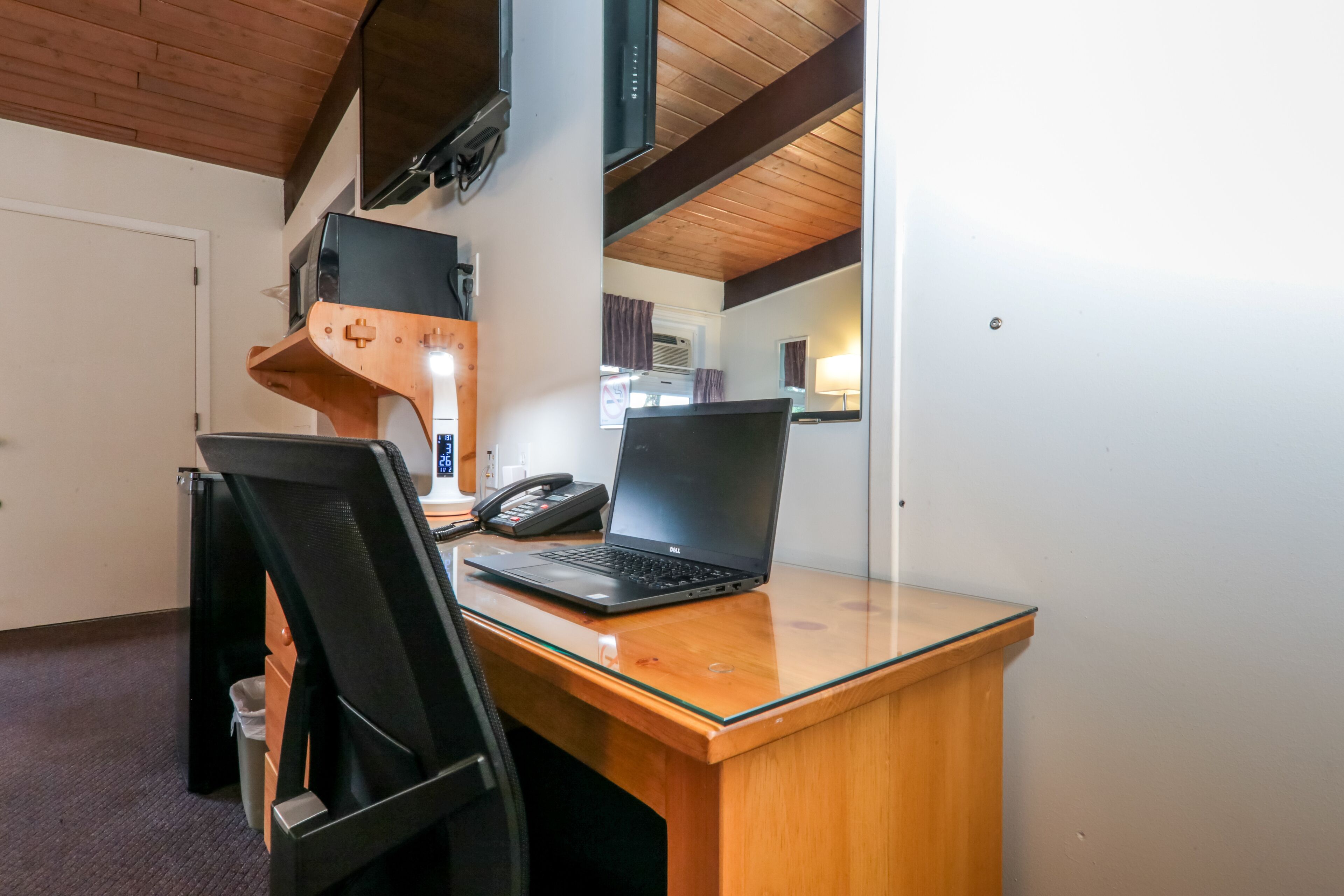 Een houten bureau met een laptop en een telefoon.