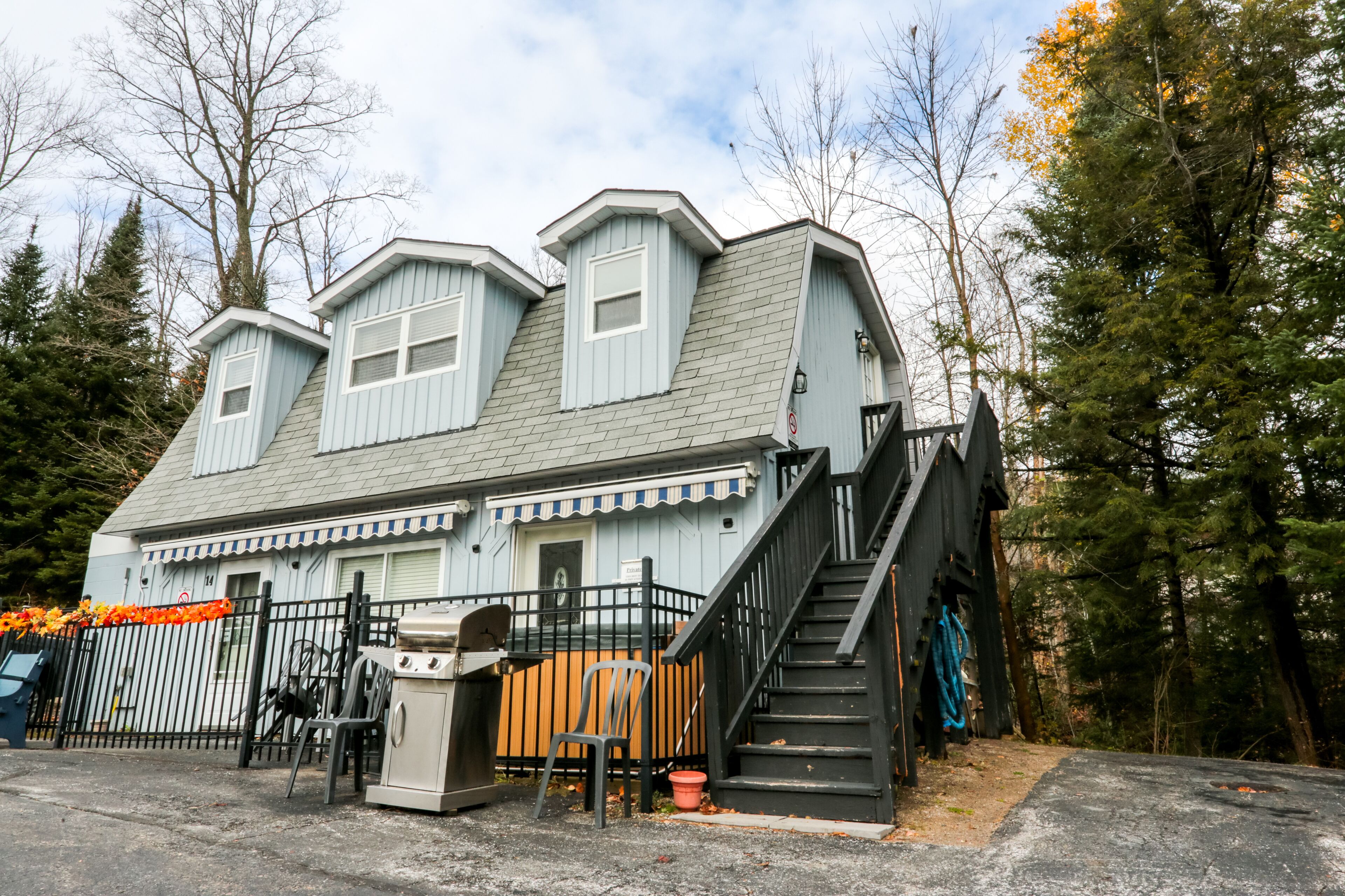 A two-story house with a steeply pitched roof, a front porch, and a staircase leading to the upper floor.