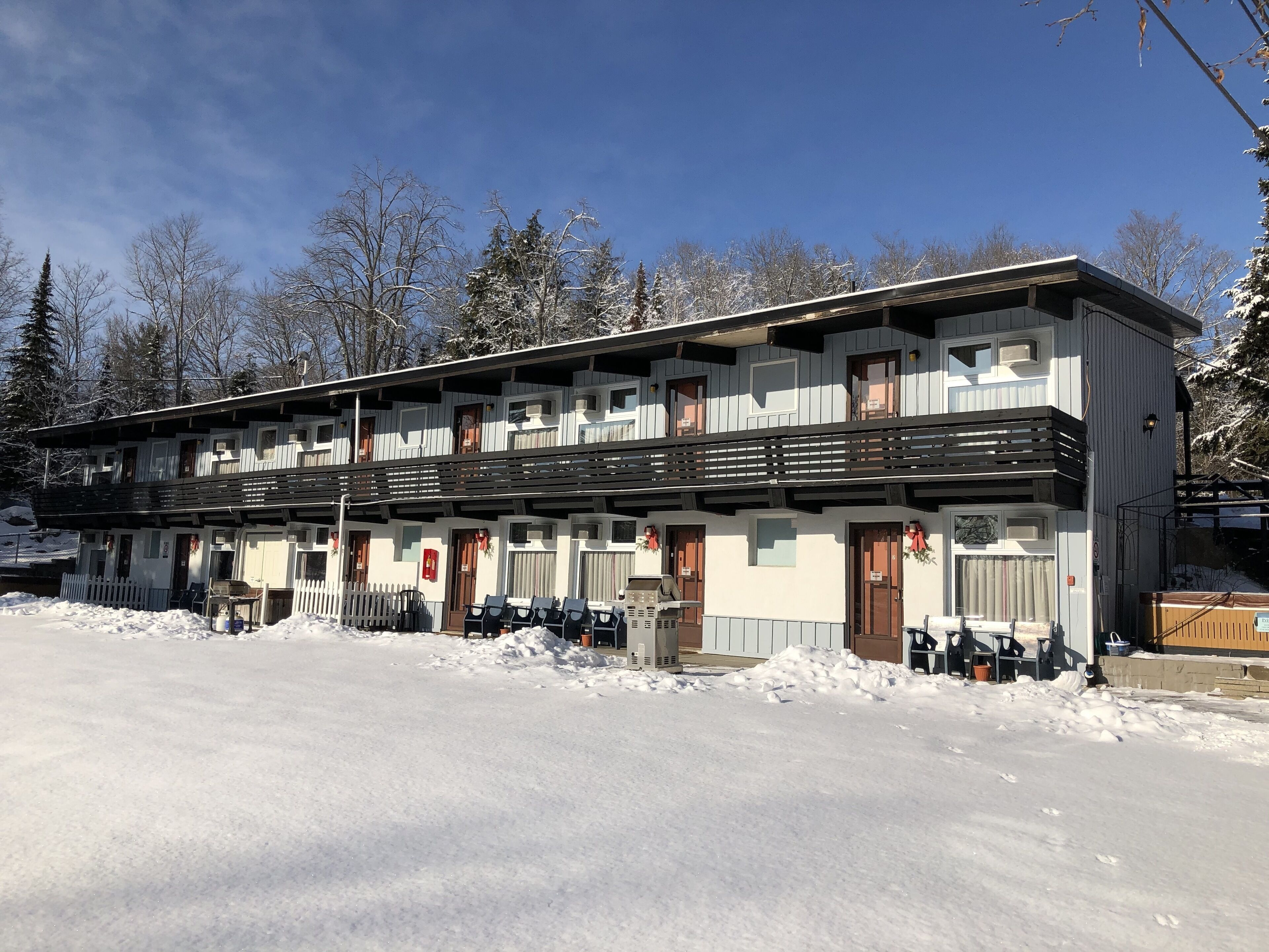 A two-story building with a balcony, multiple windows, and a snow-covered ground.