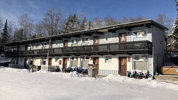 A two-story building with a balcony, multiple windows, and a snow-covered ground.