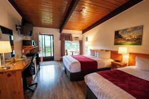A hotel room with two beds, a desk with a computer, a TV, and a painting on the wall.
