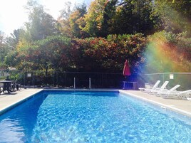 Una piscina al aire libre, sillones reclinables de piscina