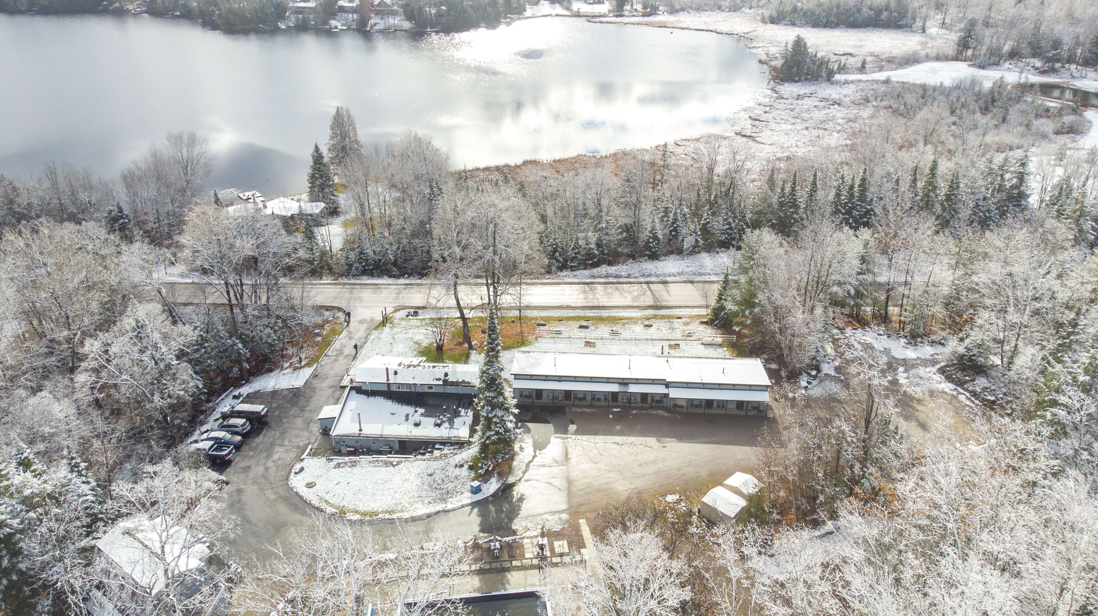 An aerial view of a building surrounded by snow-covered trees and a lake.