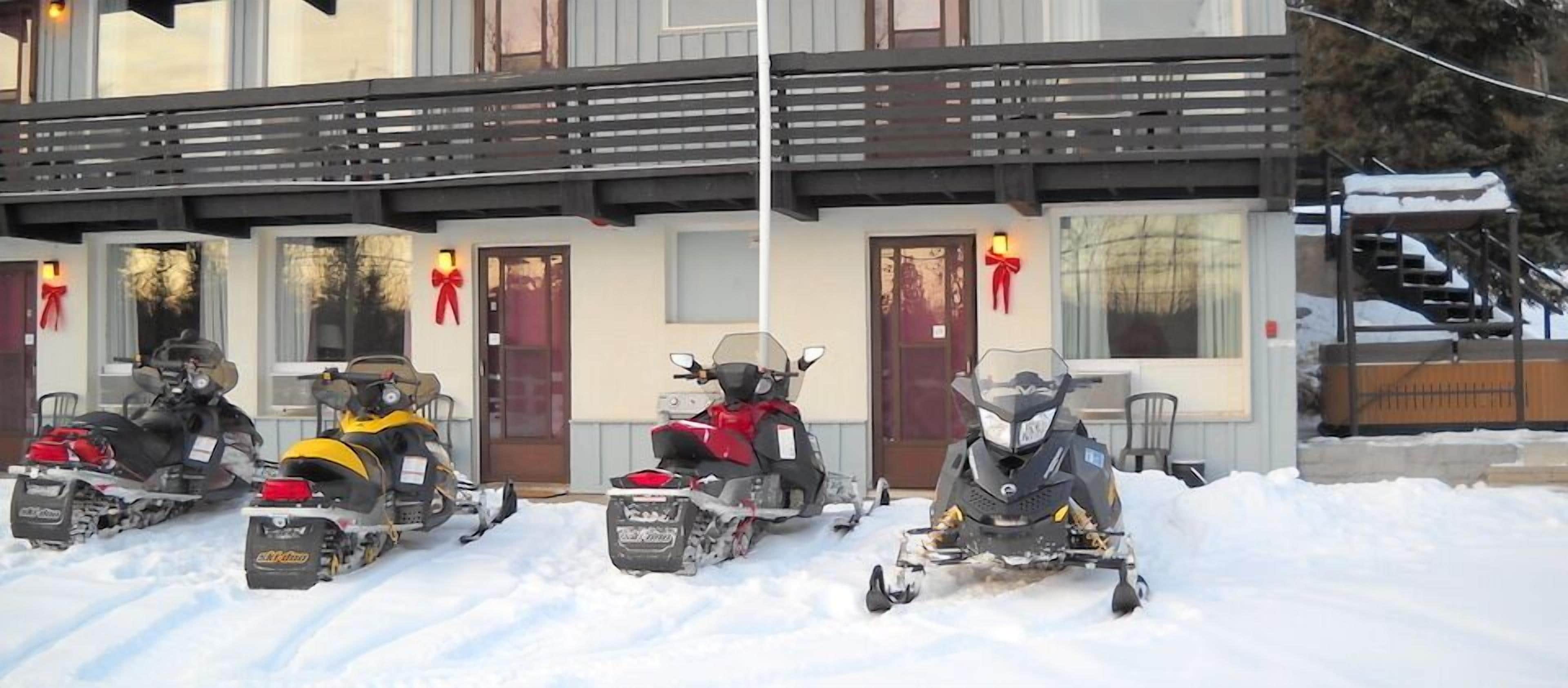 A building with a covered porch and four snowmobiles parked in front.