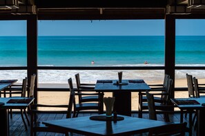 A beachside restaurant with tables and chairs facing the ocean. - Bayview The Beach Resort (Ngapali)