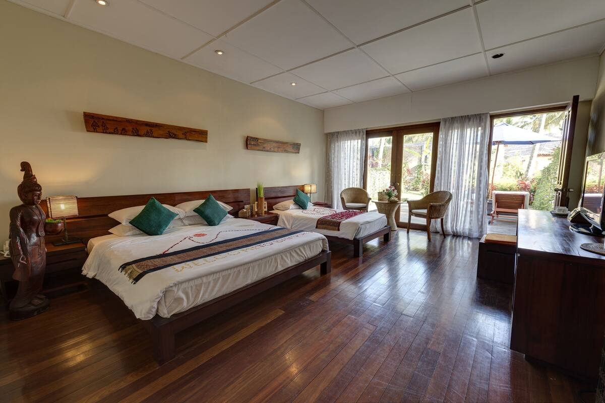 A hotel room with two beds, a desk, and a large window with curtains.