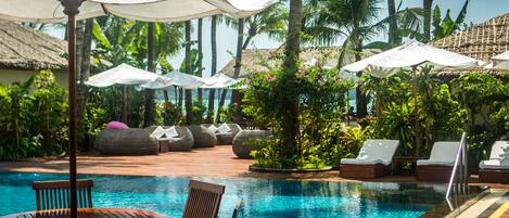 A pool area with lounge chairs, umbrellas, and a wooden deck.