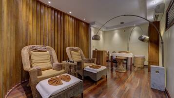 Relax in a traditional space with a warm wooden panel wall, two comfortable armchairs, and a small table for refreshments.