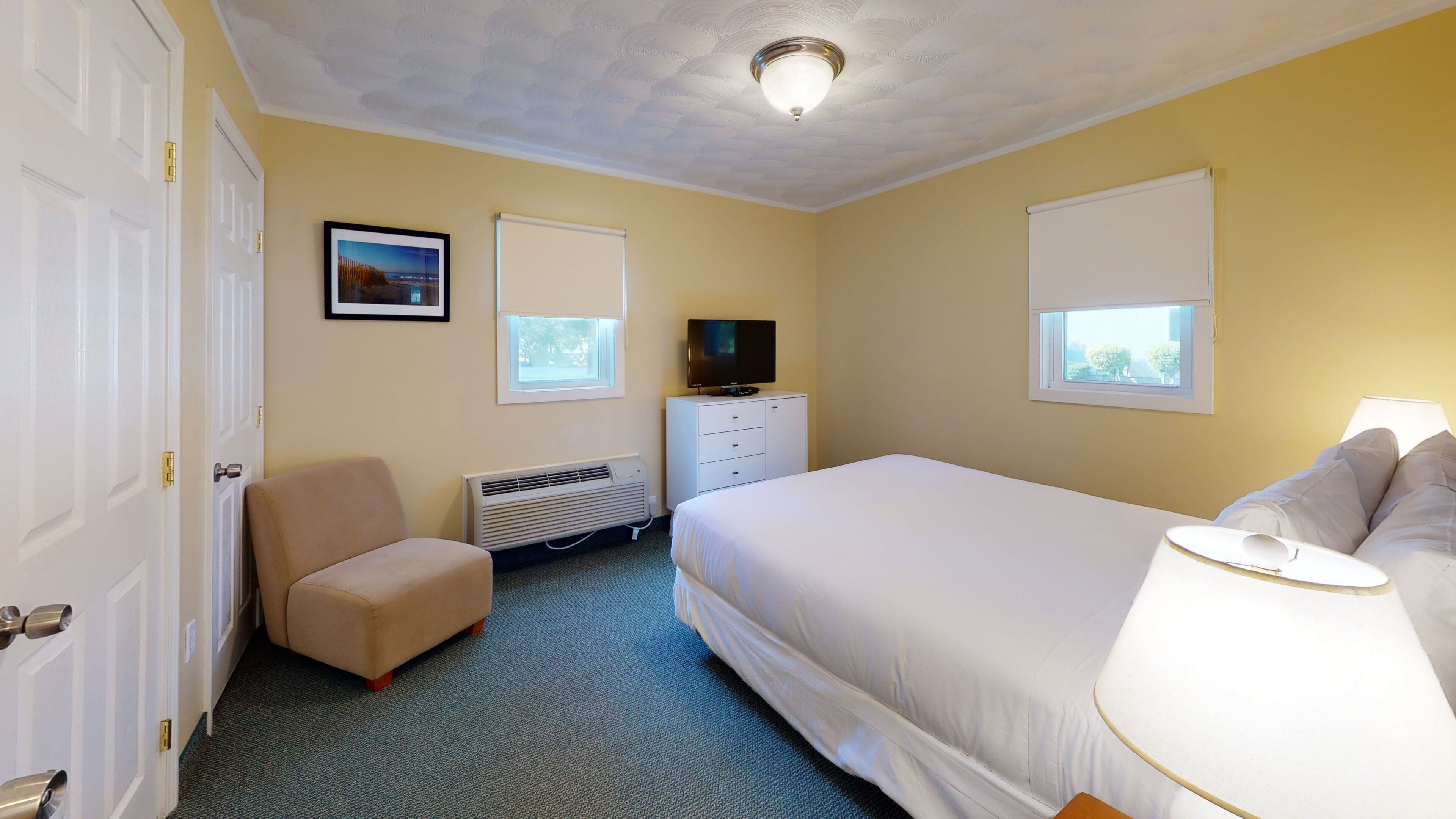 Ein Hotelzimmer mit Bett, Sessel, Fernseher und Heizung.
