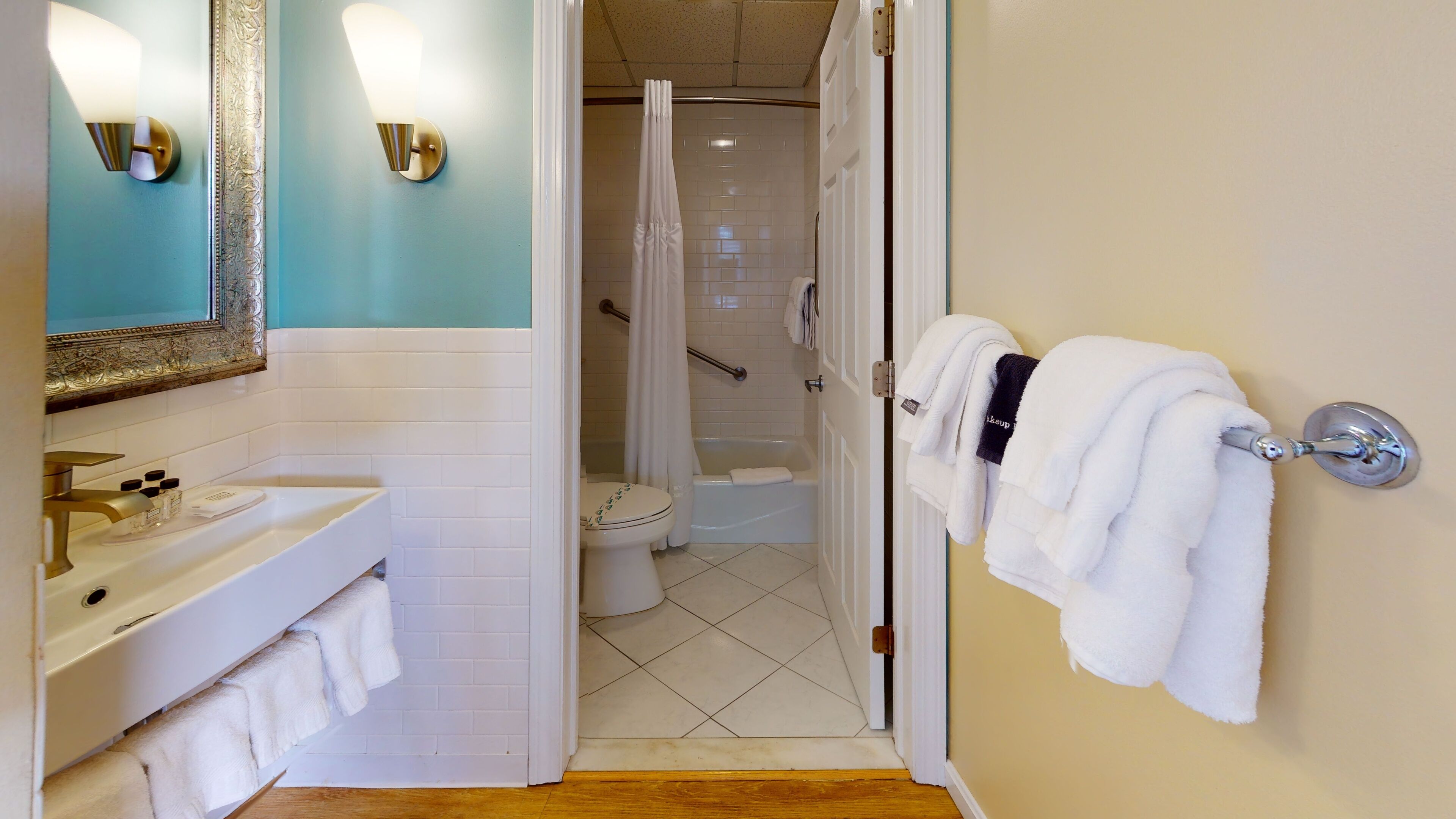 A bathroom with a sink, toilet, and bathtub. There are towels hanging on the wall and a shower curtain.