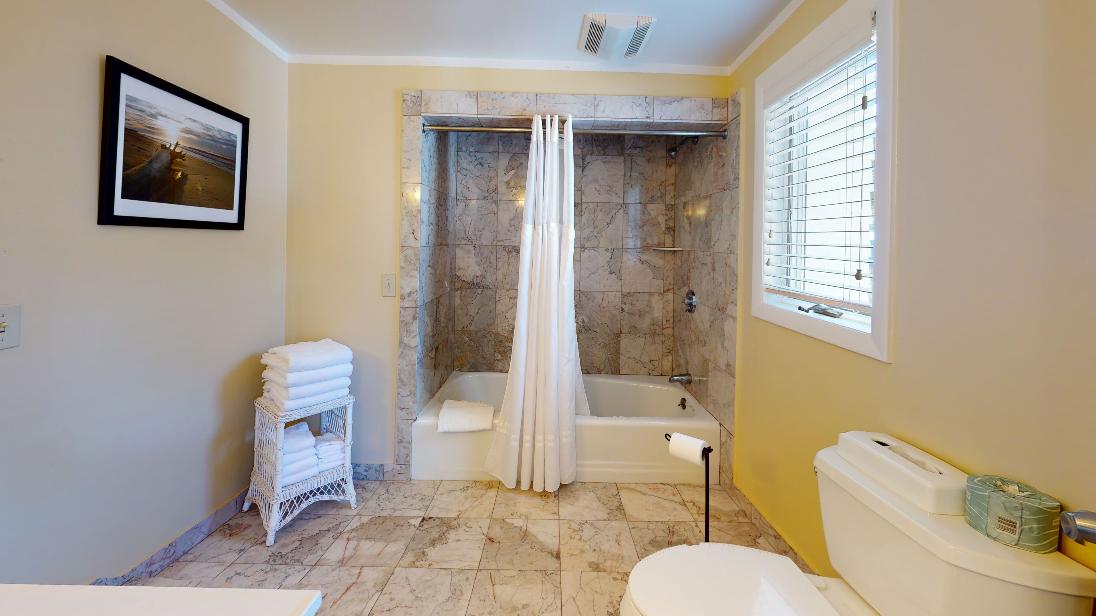 A bathroom with a bathtub, a toilet, and a shower area with a curtain.