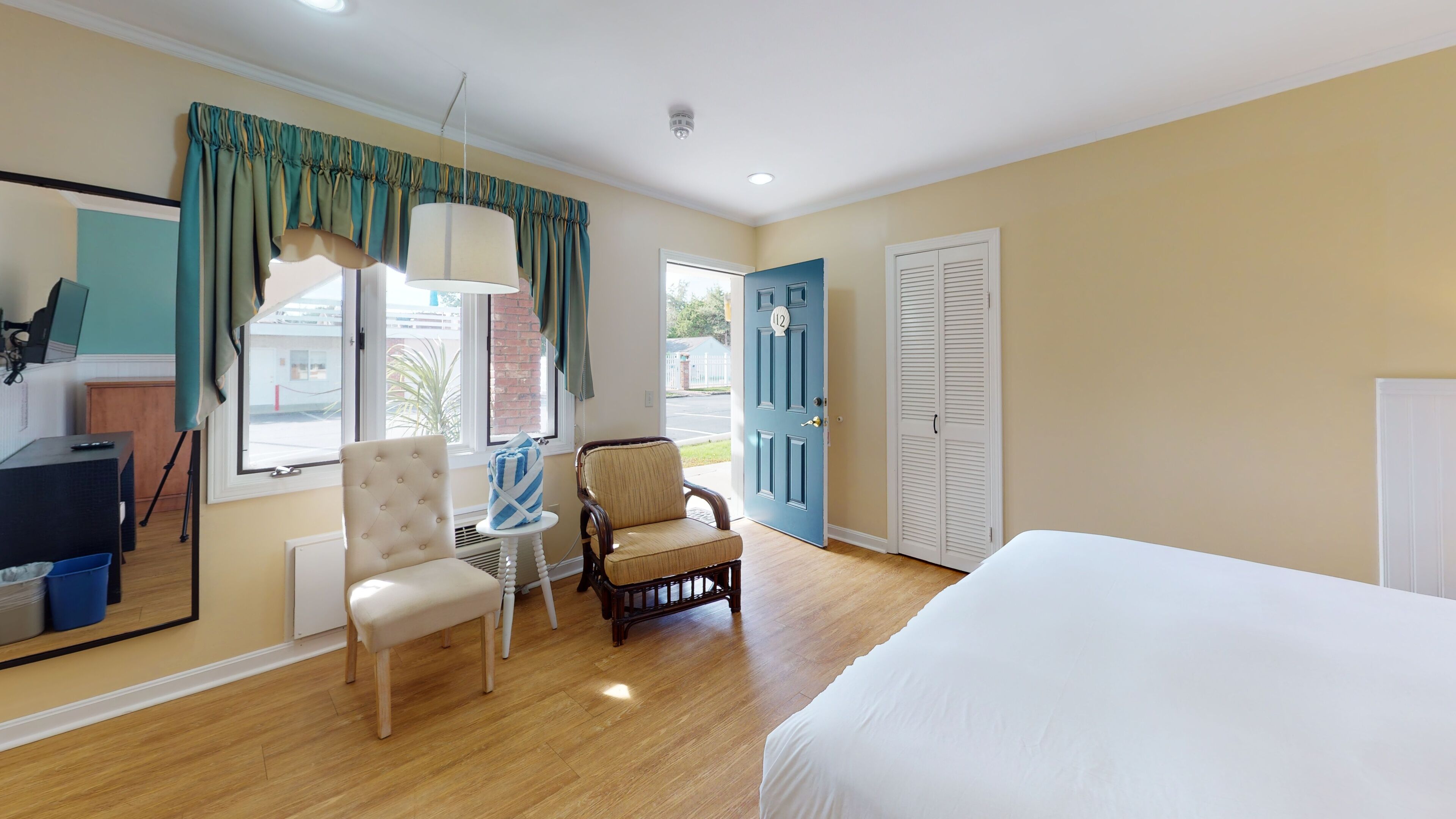 Habitación de hotel con cama, una silla, una mesita y una ventana con cortinas.