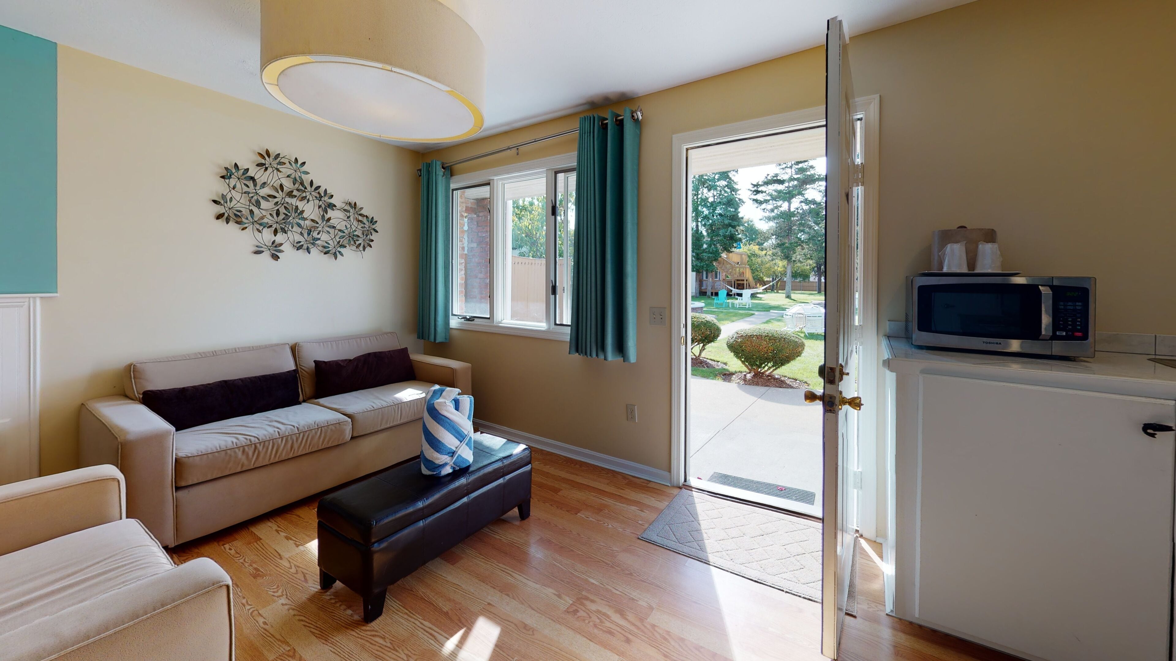 A living room with a sofa, a coffee table, and a dining area with a microwave.