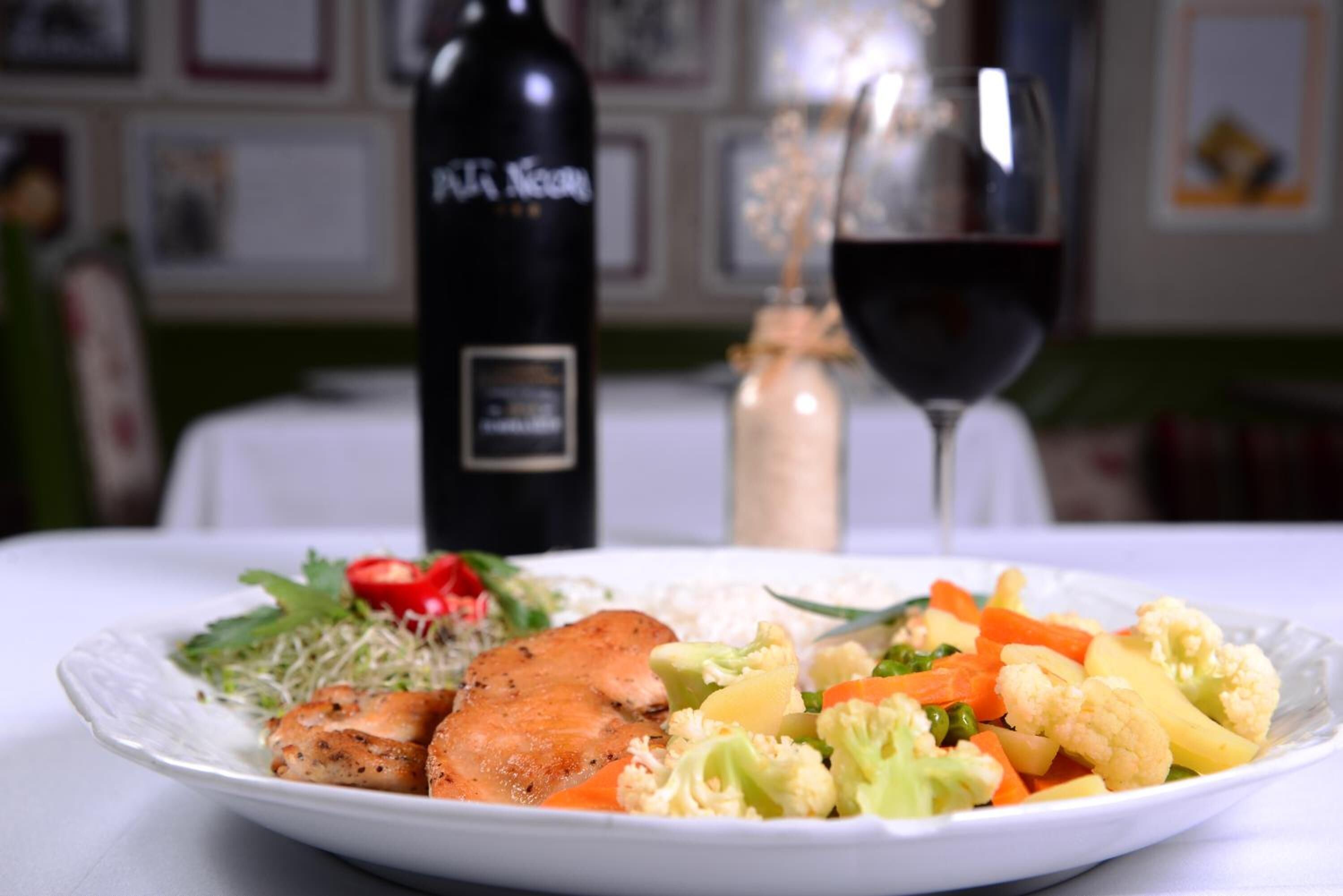 Un plato de comida con una botella y una copa de vino sobre una mesa.