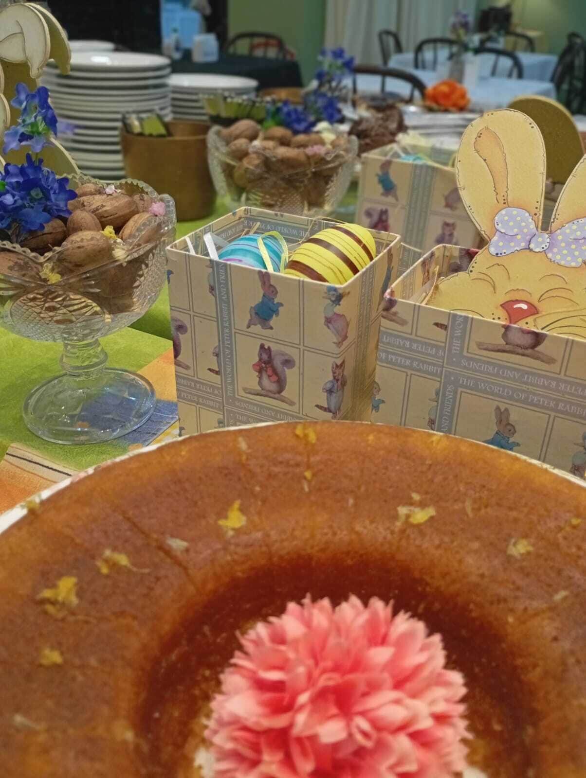 Una mesa con un pastel, un bol de galletas y una caja con un diseño de conejo.
