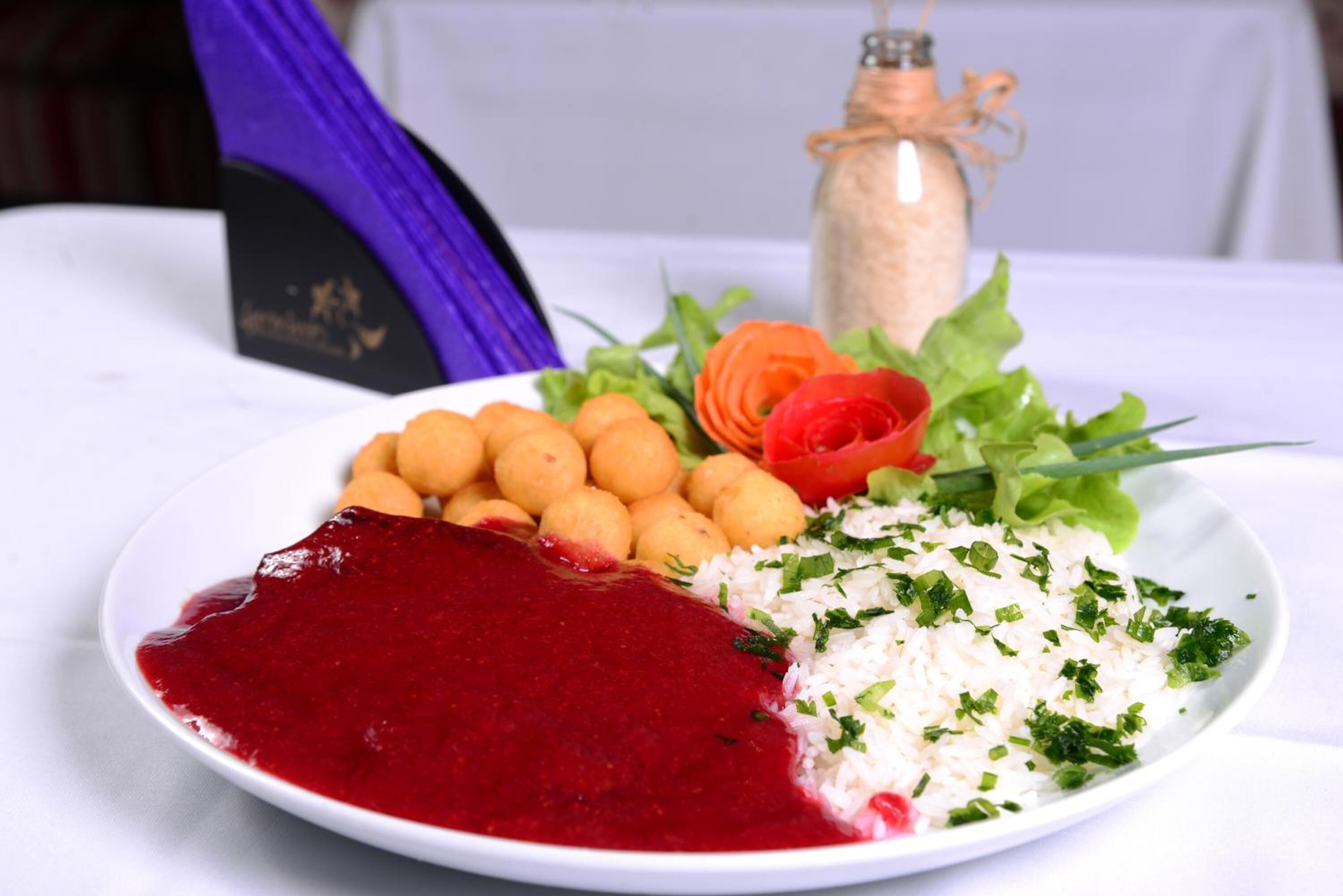 Ein Teller Essen mit roter Soße, Reis und Gemüse.