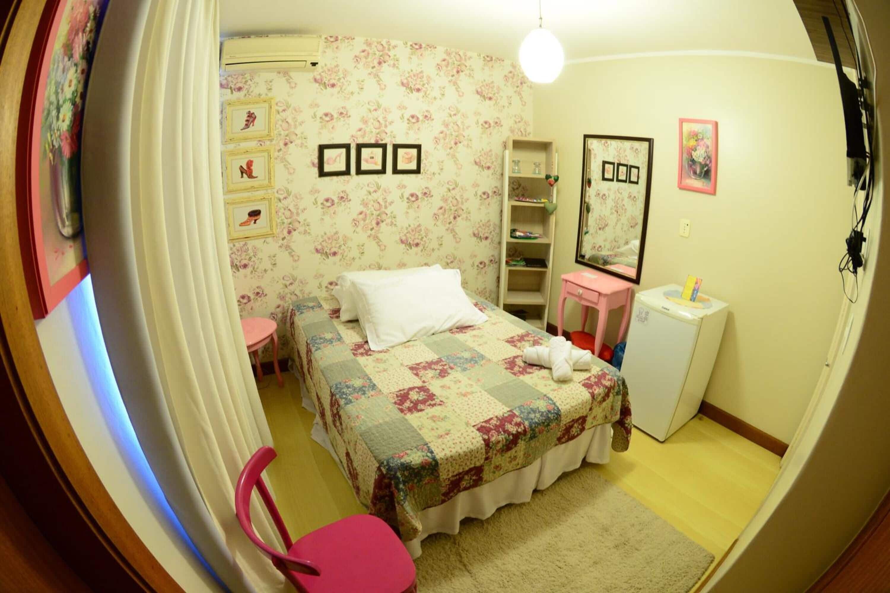 Un dormitorio con cama, un escritorio pequeño, una silla, un armario y un espejo.