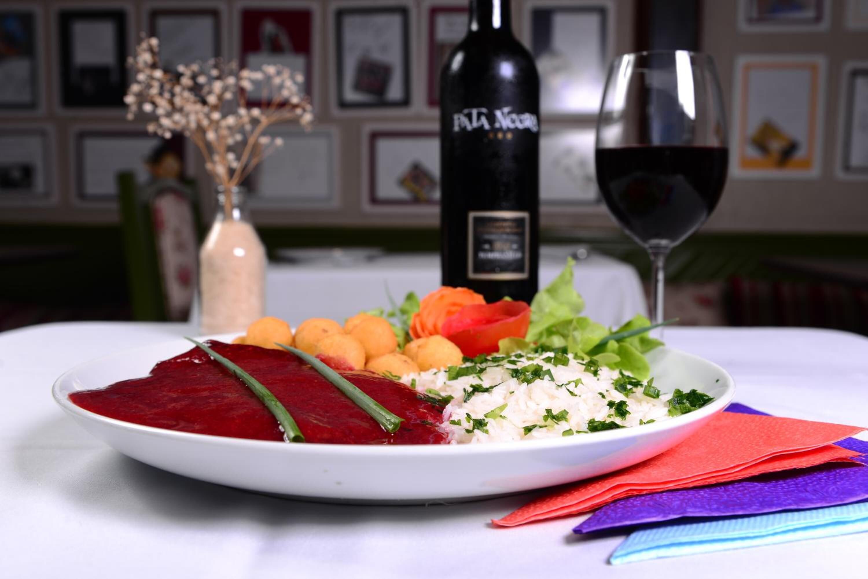 Un plato de comida con una botella de vino y una copa de vino sobre una mesa.