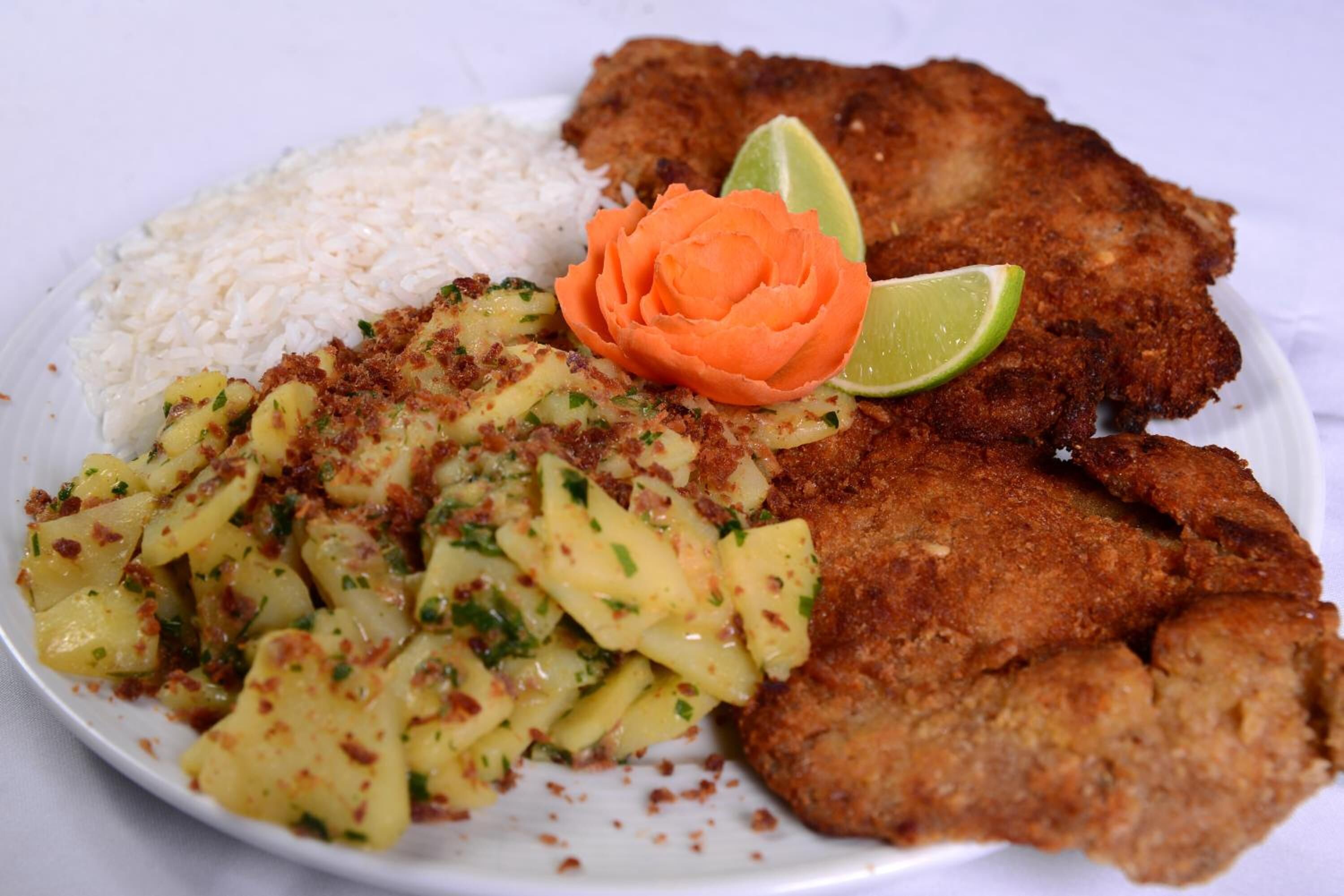A plate with fried chicken, rice, and a potato dish garnished with herbs.