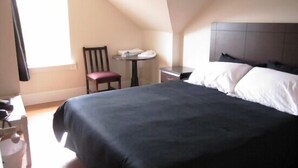 A bedroom with a bed, a chair, a small table, and a window. - Bk Guest house (Anacortes)