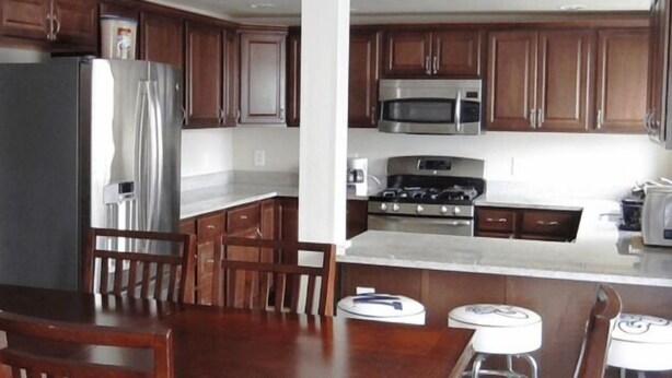 A kitchen with wooden cabinets, a stainless steel refrigerator, a microwave, and a stove. - Bk Guest house (Anacortes)